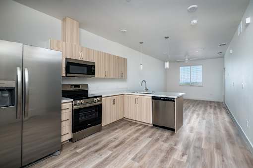 A modern kitchen with wooden floors and stainless steel appliances.