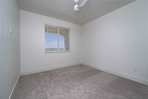 A room with a ceiling fan and carpeted floor.