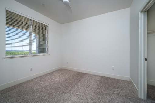 A room with a window and a fan on the ceiling.