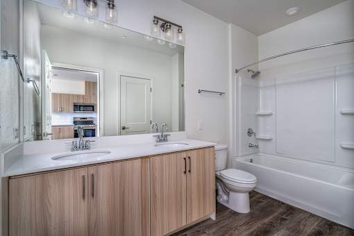 A modern bathroom with a wooden vanity and white countertop.