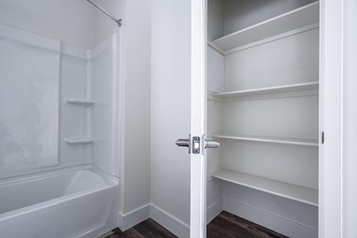 A white bathroom with a white bathtub and a white walk in closet.