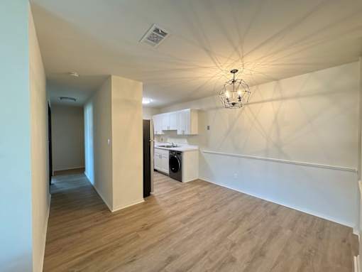 A room with wooden flooring and a chandelier hanging from the ceiling.