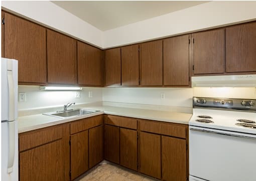 A kitchen with brown cabinets and white appliances.