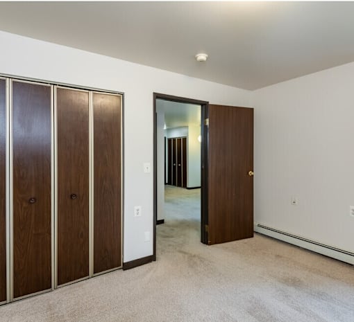 A room with a white wall and a brown door.