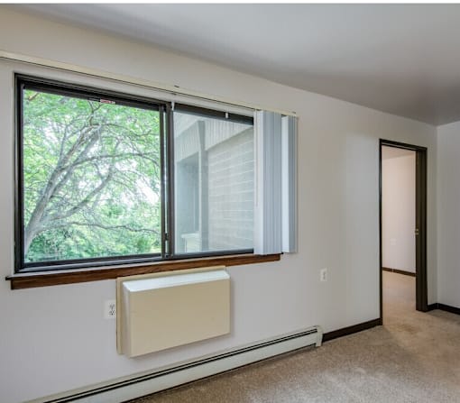 A window with a white blind and a window air conditioner unit.