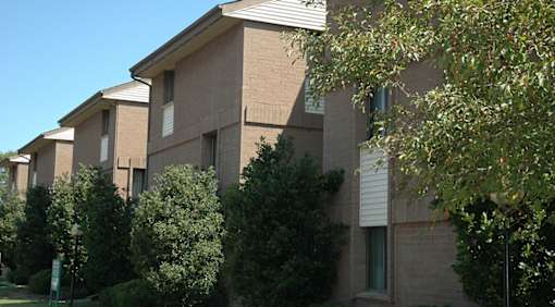 A building with a brown facade and green trees in front.