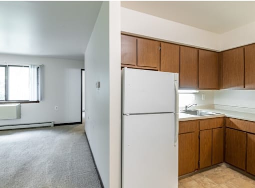 A white refrigerator in a kitchen with wooden cabinets.