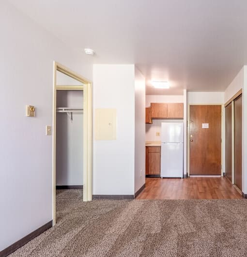 A kitchen area with a refrigerator, cabinets, and a doorway leading to another room.