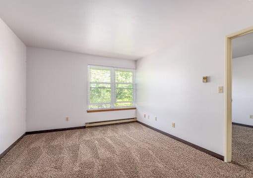 A room with a window and carpeted floor.