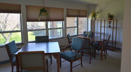A room with a table and chairs in front of a window.