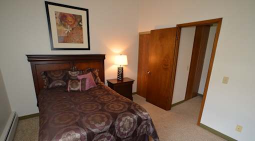 A bedroom with a bed, a lamp, and a painting on the wall.