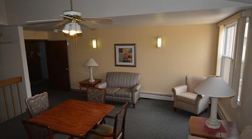 A living room with a ceiling fan and a painting on the wall.