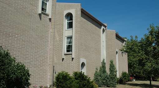 A large grey building with a few windows and a few trees in front.
