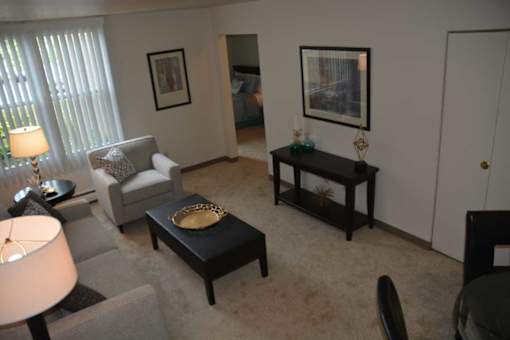 A living room with a grey couch, a black coffee table, and a lamp.