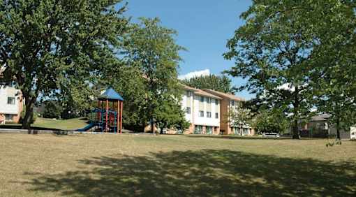 A playground with a slide is in front of a building.