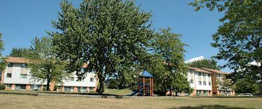 A playground with a blue roof is surrounded by trees and apartment buildings.