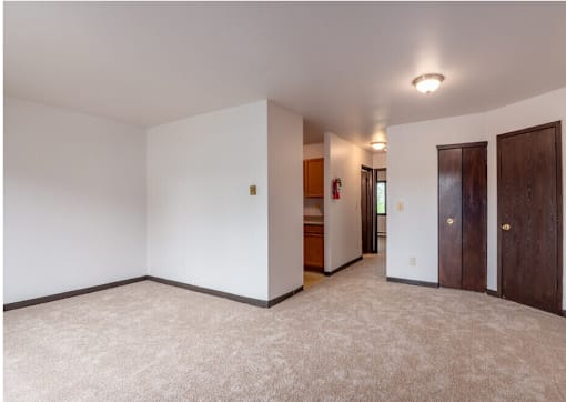 A white room with a carpeted floor and a door on the right side.