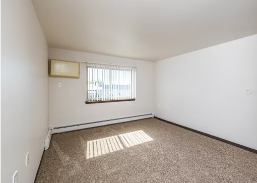 A room with a window and carpeted floor.