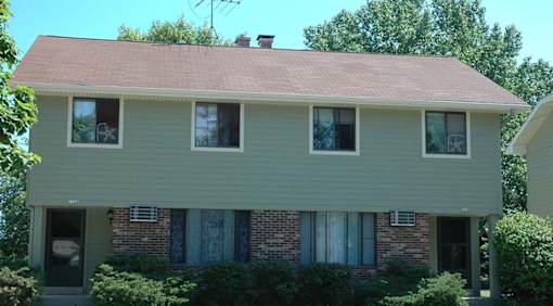 A house with a green siding and a red roof.