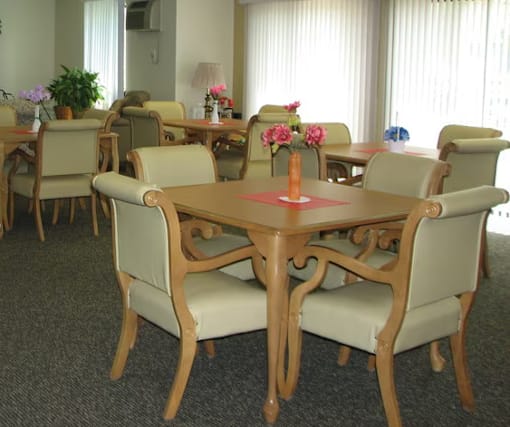 A dining room with a table surrounded by chairs.