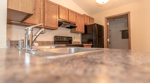 A kitchen with a granite countertop and wooden cabinets.