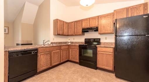 A kitchen with black appliances and wooden cabinets.