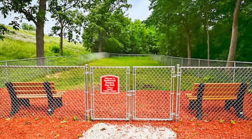 A sign is on a fence in front of a park.