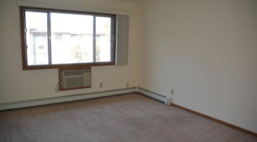 A room with a window and a wall-mounted air conditioner unit.