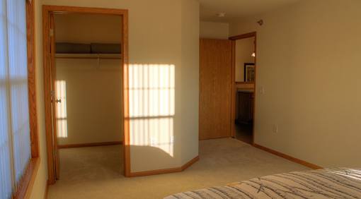 A bedroom with a large bed and a full-length mirror.