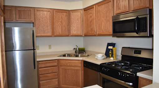 A kitchen with wooden cabinets and a stainless steel refrigerator.