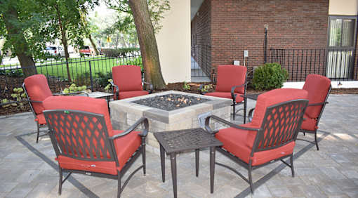 A patio with a fire pit and chairs.