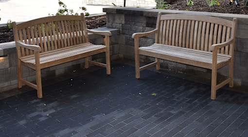 Two wooden benches are placed on a patio.