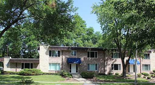 A building with a blue awning is surrounded by trees.