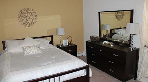 A bedroom with a bed, nightstand, and dresser.