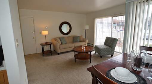 A living room with a couch, chair, and dining table.