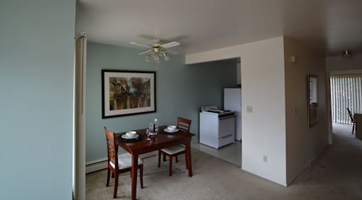 A dining room with a table set for two and a painting on the wall.
