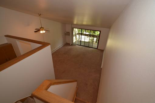 A room with a ceiling fan and a window with bars.