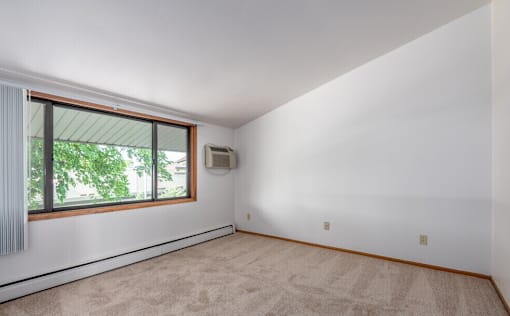 A room with a window and carpet on the floor.