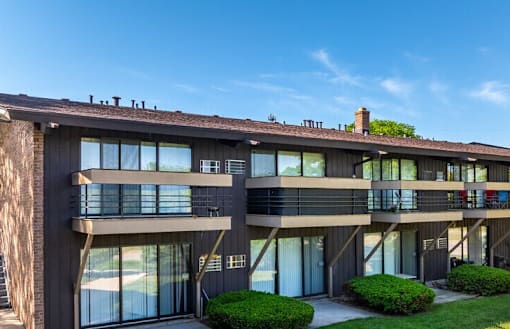A modern building with a balcony and a green lawn in front.