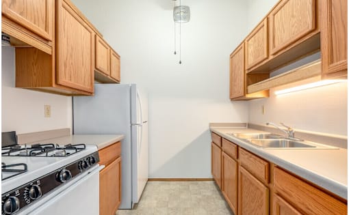 A kitchen with a white gas stove and wooden cabinets.