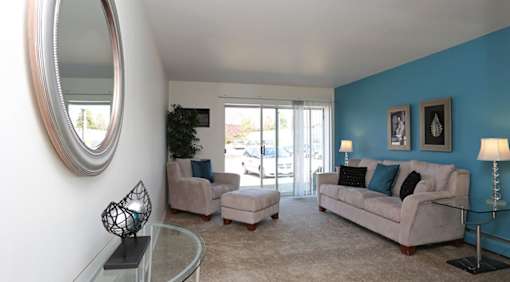 A living room with a white couch and a glass coffee table.