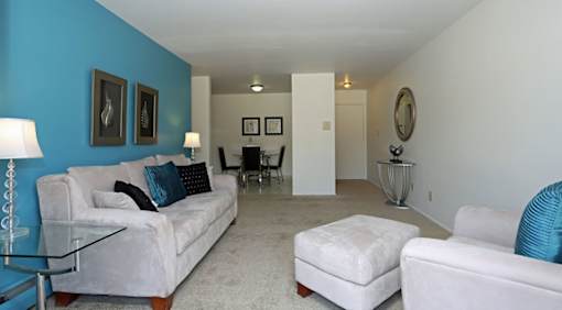 A living room with white couches and a glass table.