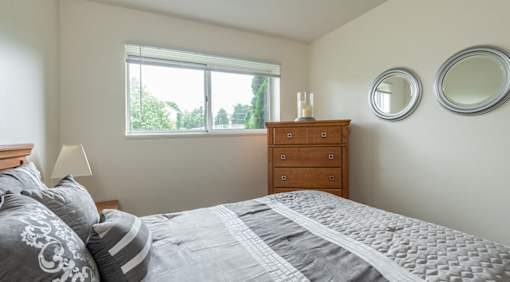 A bedroom with a bed, dresser, and two round mirrors on the wall.