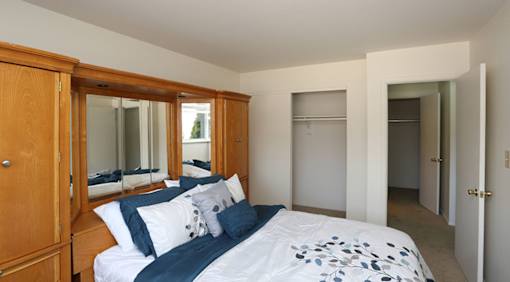 A bedroom with a large bed and a wooden wardrobe.
