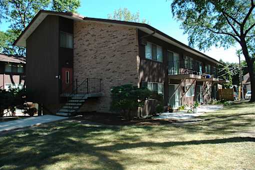 A brown house with a red door and a balcony.