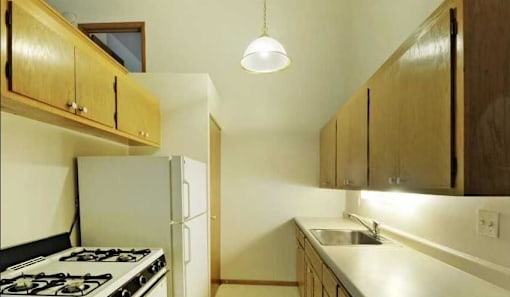 A kitchen with a stove, sink, and cabinets.