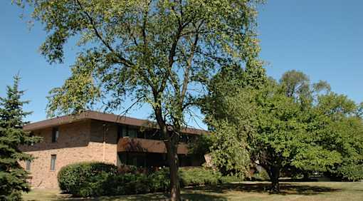 A house with a brown roof and a tree in front of it.
