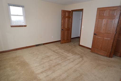 A room with a carpeted floor and two wooden doors.