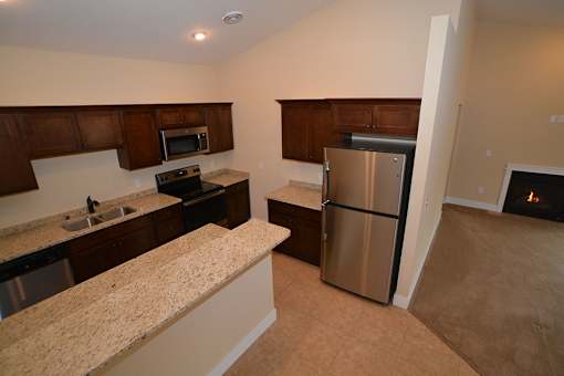 A kitchen with a refrigerator, sink, and microwave.
