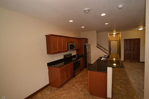 A kitchen with brown cabinets and black countertops.